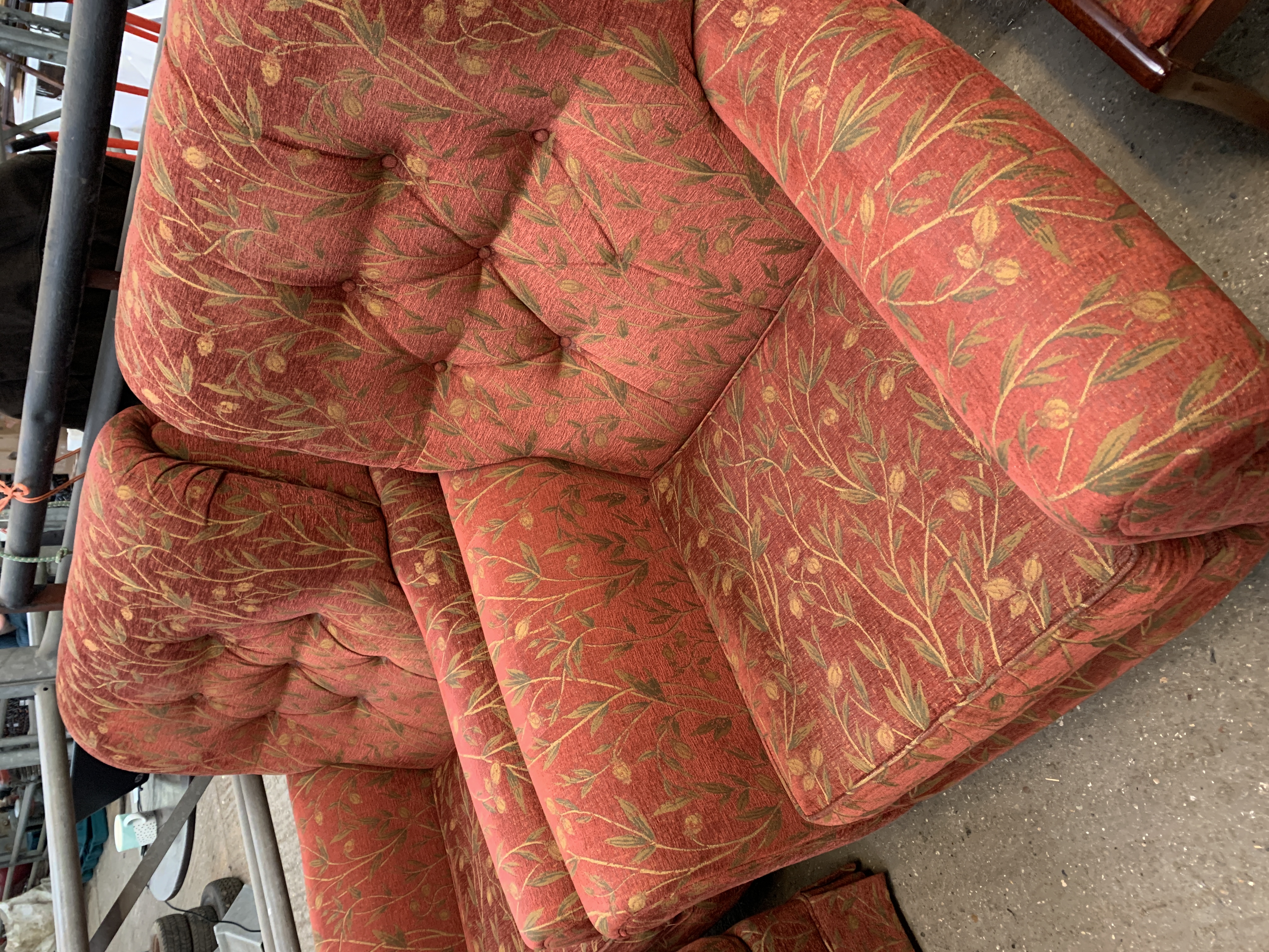 Two armchairs and an ottoman upholstered in dark red and gold floral design.