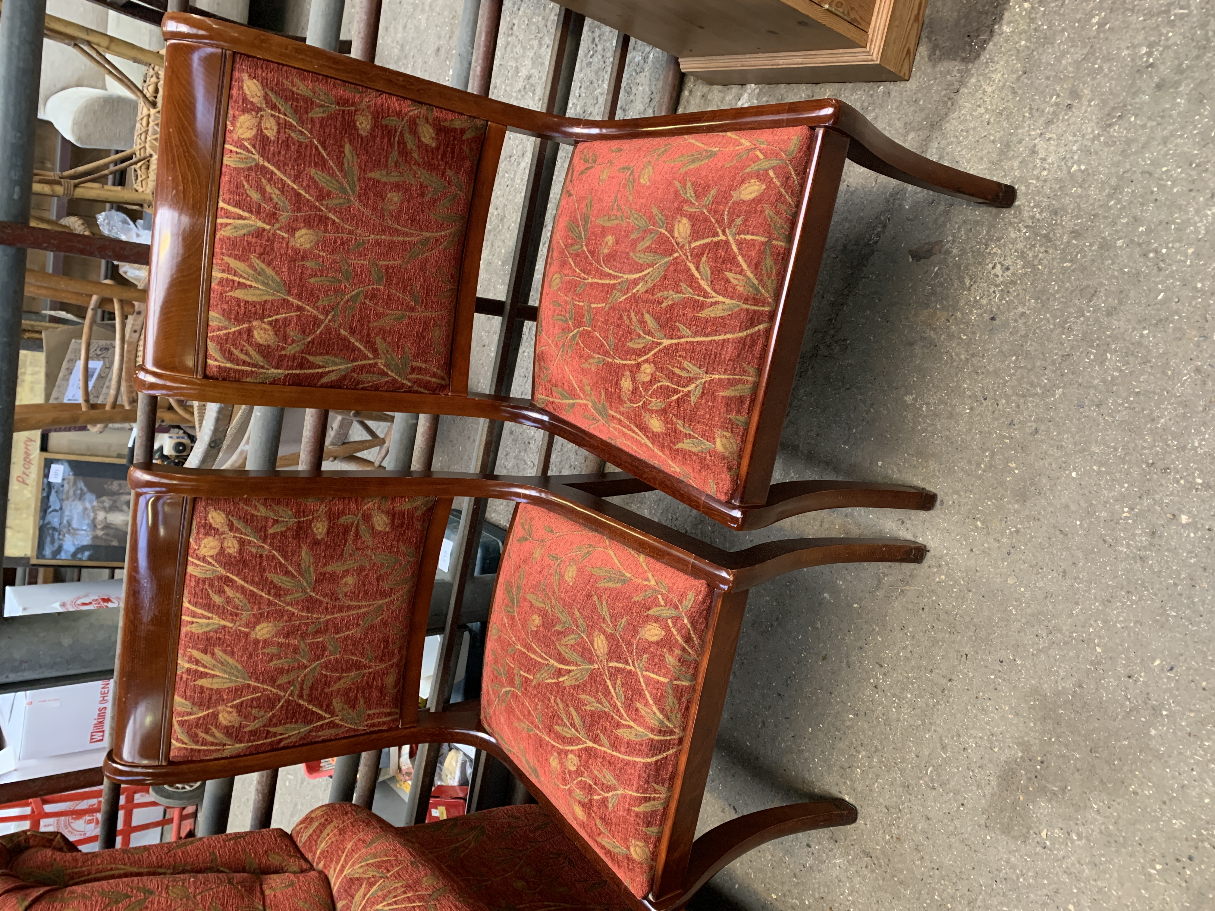 Pair of dining chairs with sabre legs upholstered in dark red and gold floral design.