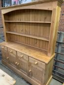 Pine dresser with two shelves above four frieze drawers over four cupboards