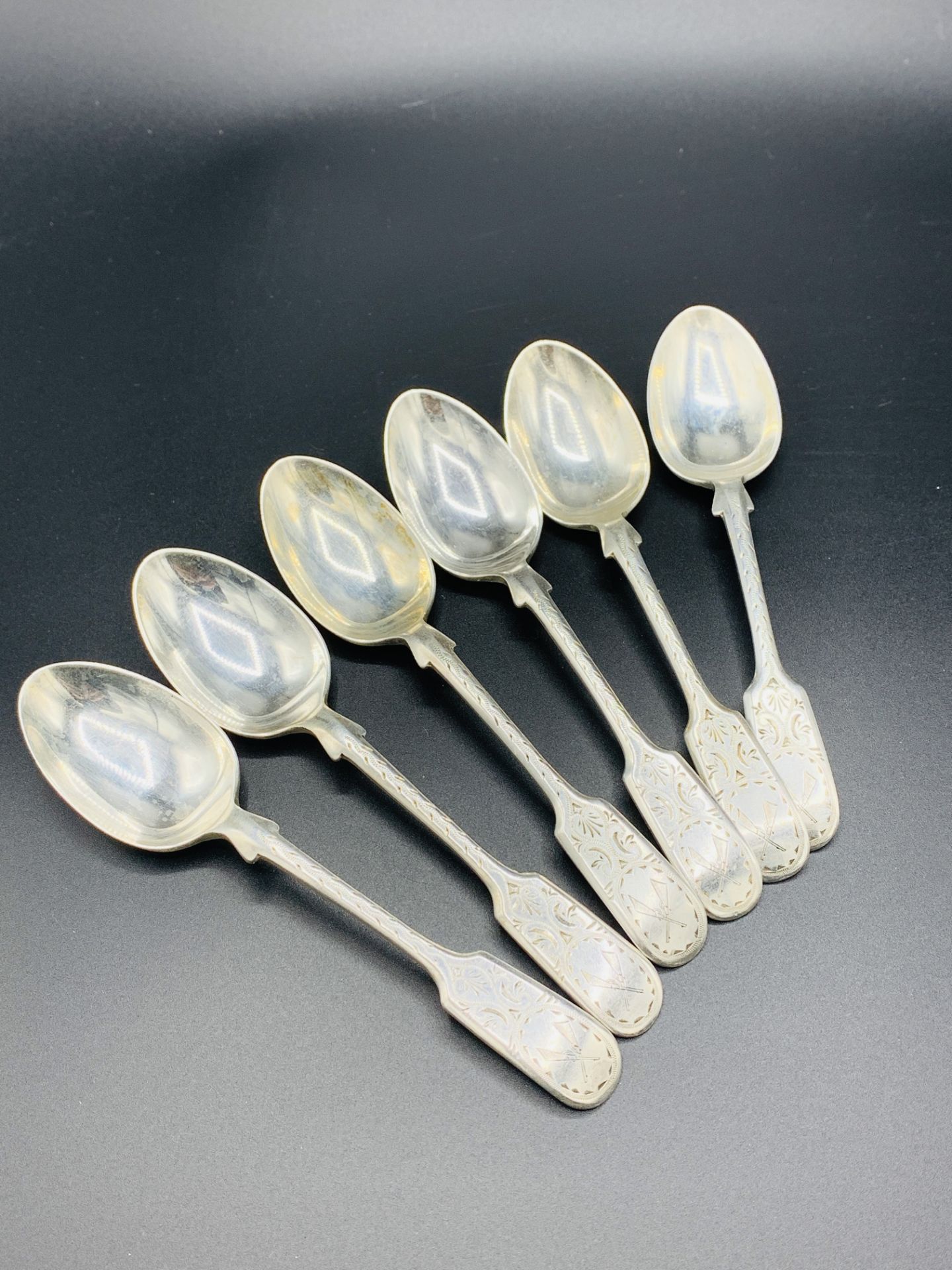 Six silver teaspoons with engraved decoration and crossed rifles to handles