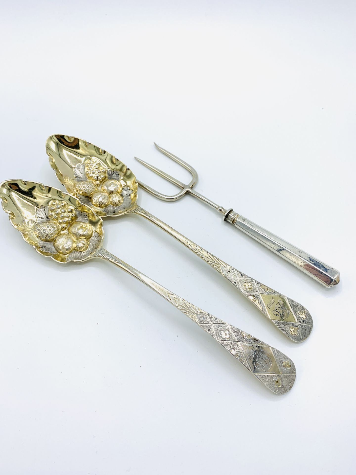 Two George III silver and gilt berry spoons and a silver 3 prong fork