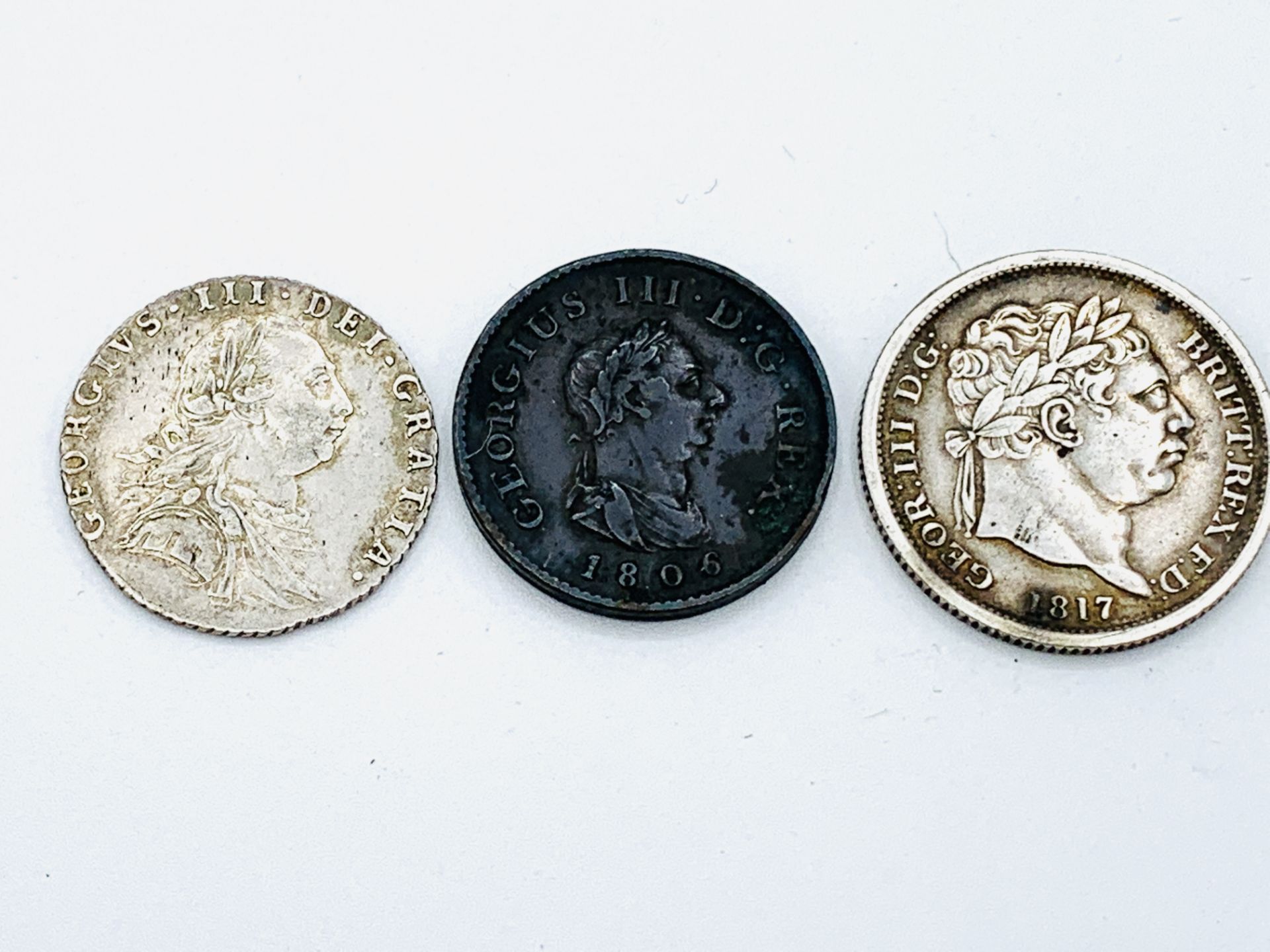 George III Silver Shilling 1787, a George III Silver Shilling 1817, and a George III penny 1806