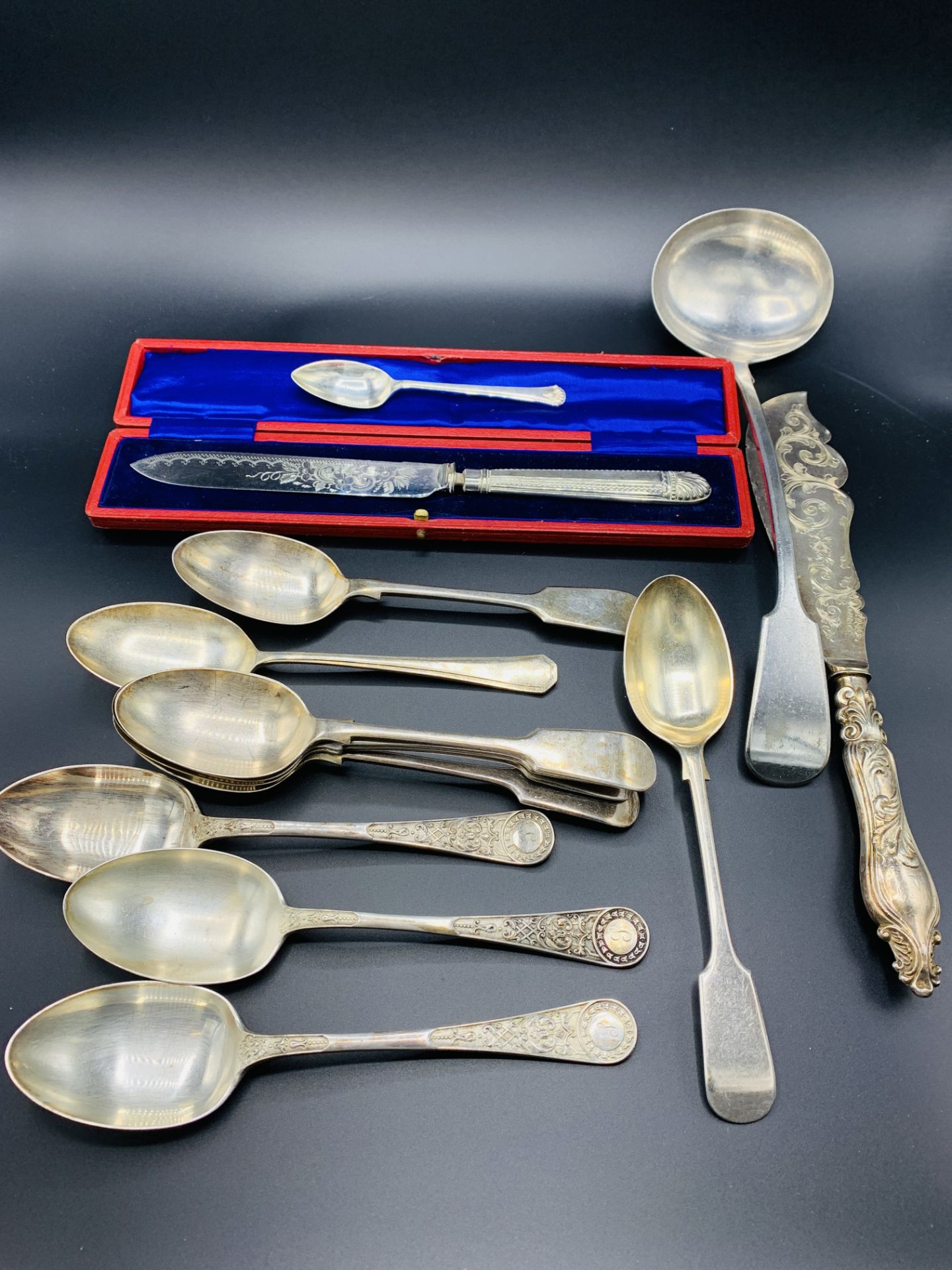 A collection of silver plate cutlery and a bronzed metal candle snuffer.