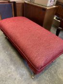 Red upholstered long footstool on casters