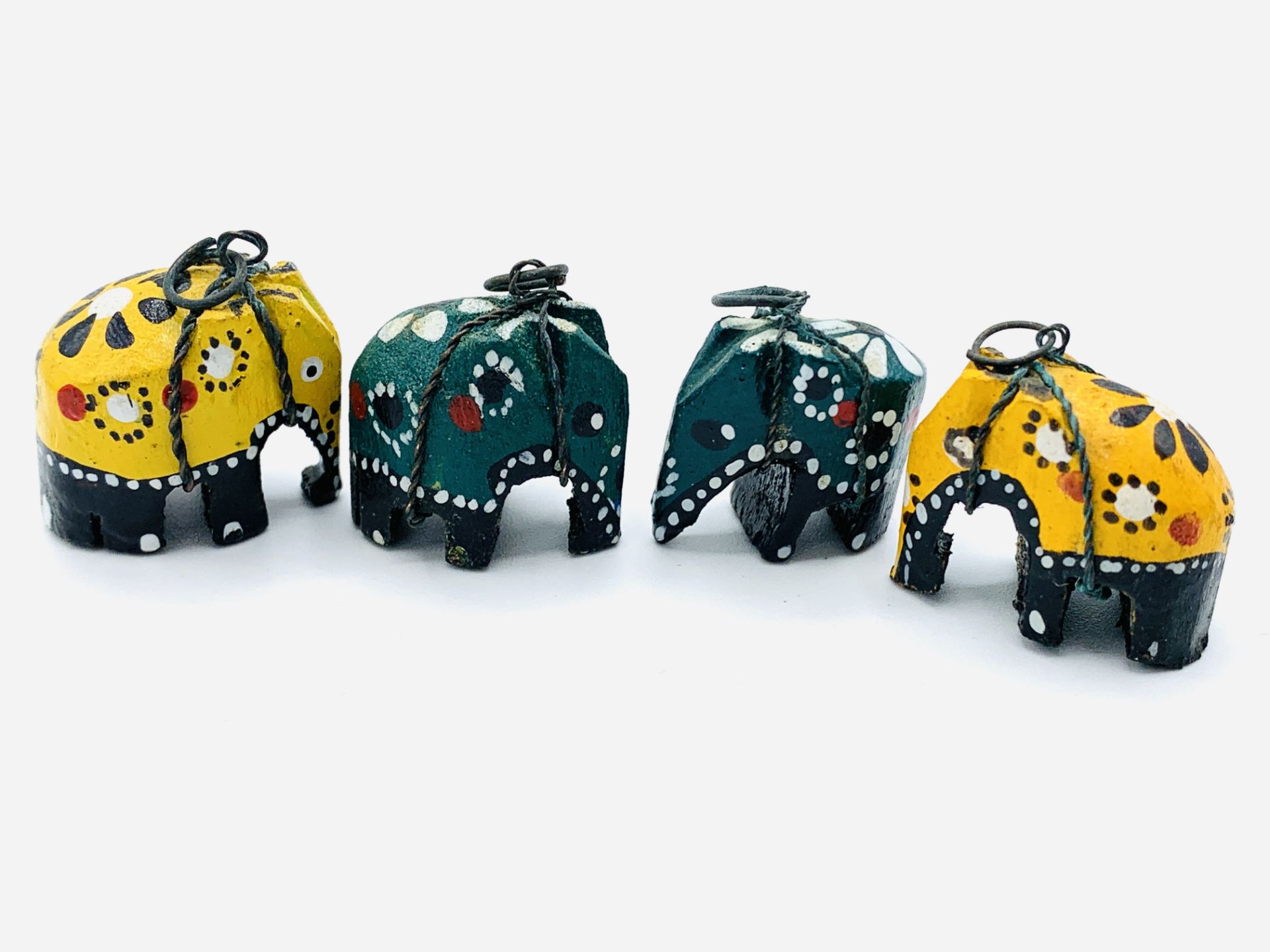 Four carved wooden elephants together with four metal rings.