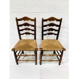 Two oak framed ladder back chairs with string seats.