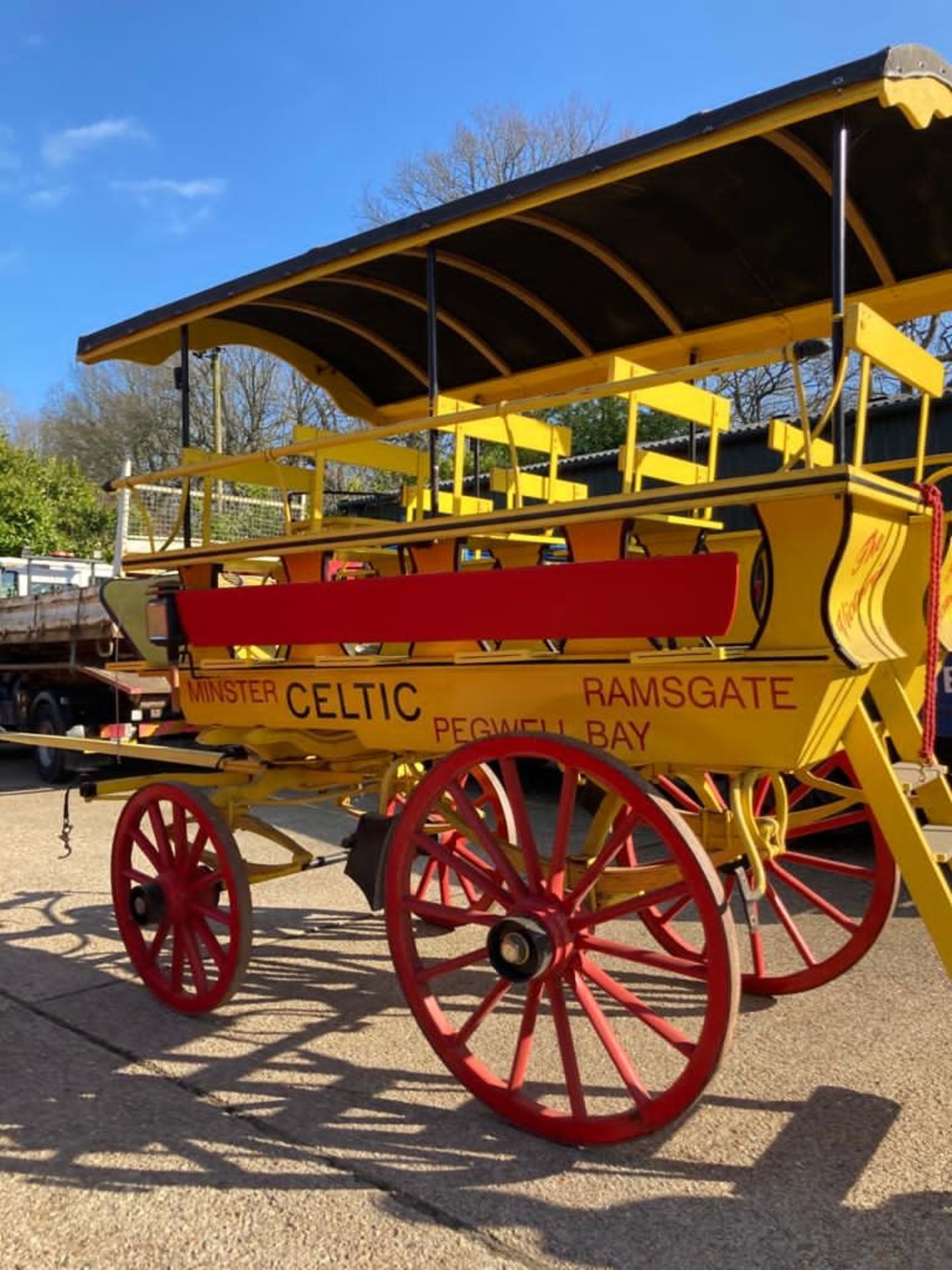 CHARABANC painted yellow and red with 21 wooden seats accessible via a rear staircase