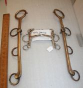 Large brass whip rack in the design of a Pelham bit.