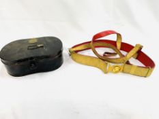 A gilt decorated red leather military belt in a black painted metal tin written C. Smith and Son