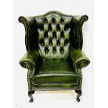 A bottle green leather button back wing back armchair