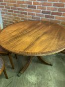 Mahogany circular tilt top dining table on pedestal to three legs with brass casters