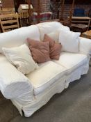 A two seater sofa upholstered in cream loose covers