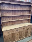 Pine dresser with three open shelves over four frieze drawers above four cupboards