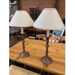 A pair of decorative candle stick-shaped metal table lamps