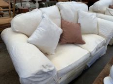 A two seater sofa upholstered in cream loose covers