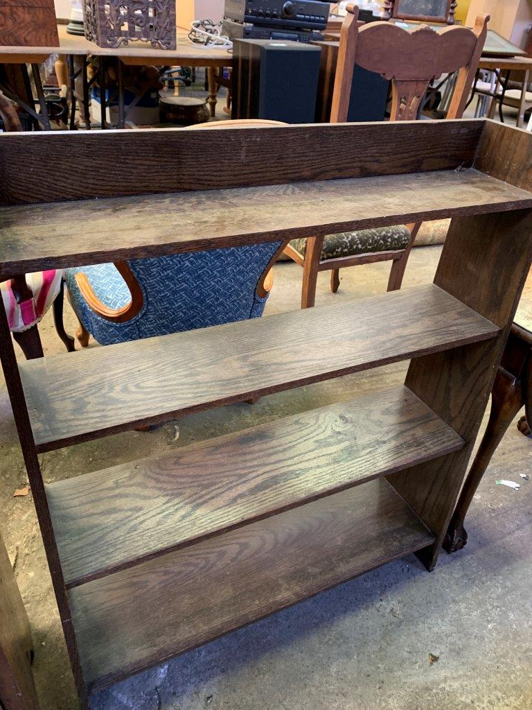 Open bookcase with four graduated shelves, and two carved implements