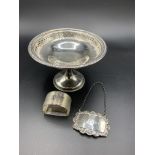 Silver dish on stand hallmarked Birmingham 1915, a napkin ring and a brandy label