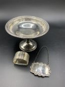 Silver dish on stand hallmarked Birmingham 1915, a napkin ring and a brandy label