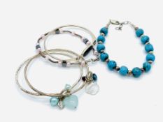 Three silver bangles and two silver bead bracelets