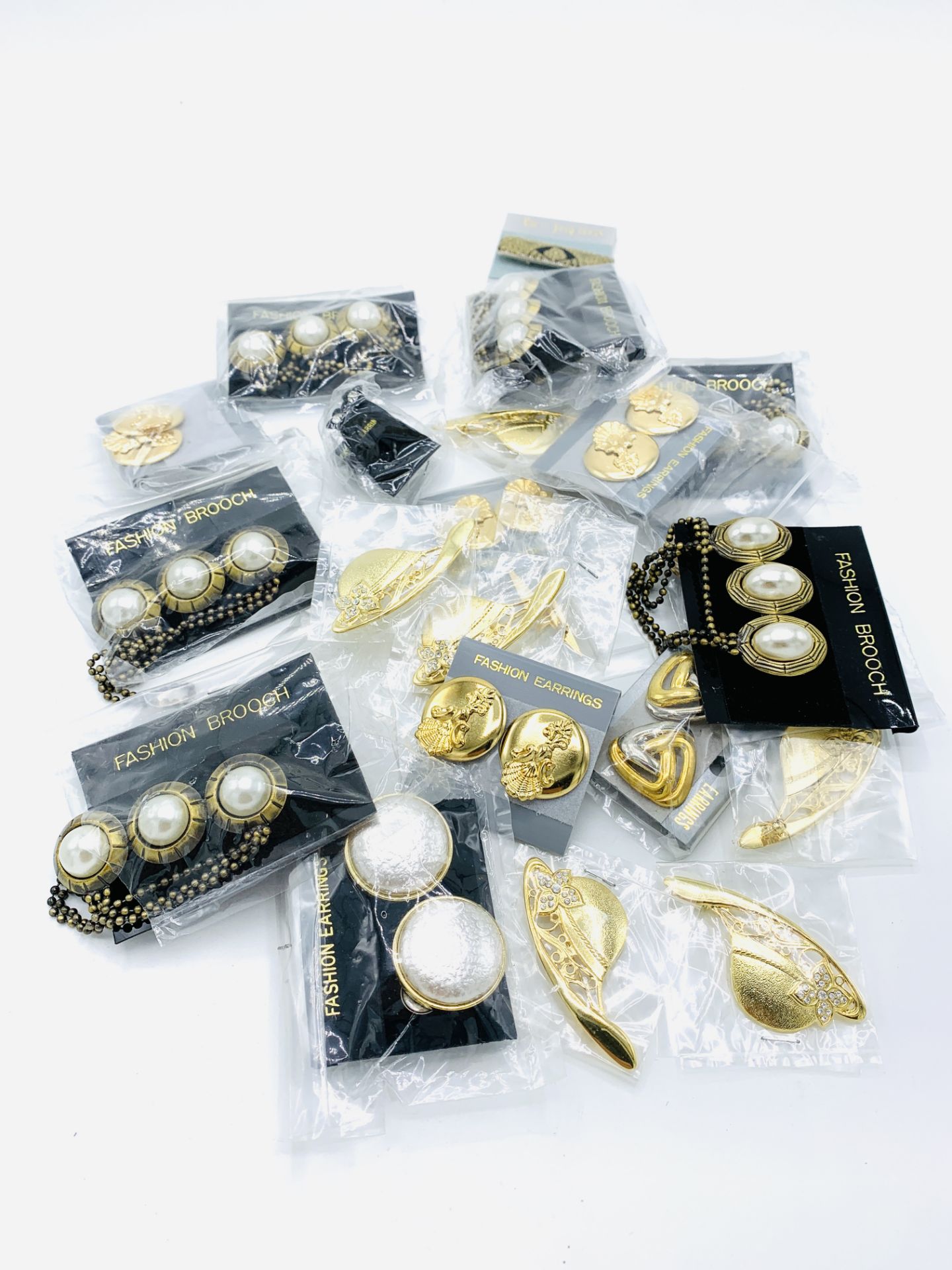 Eight pairs of fashion earrings and fifteen costume brooches, all new