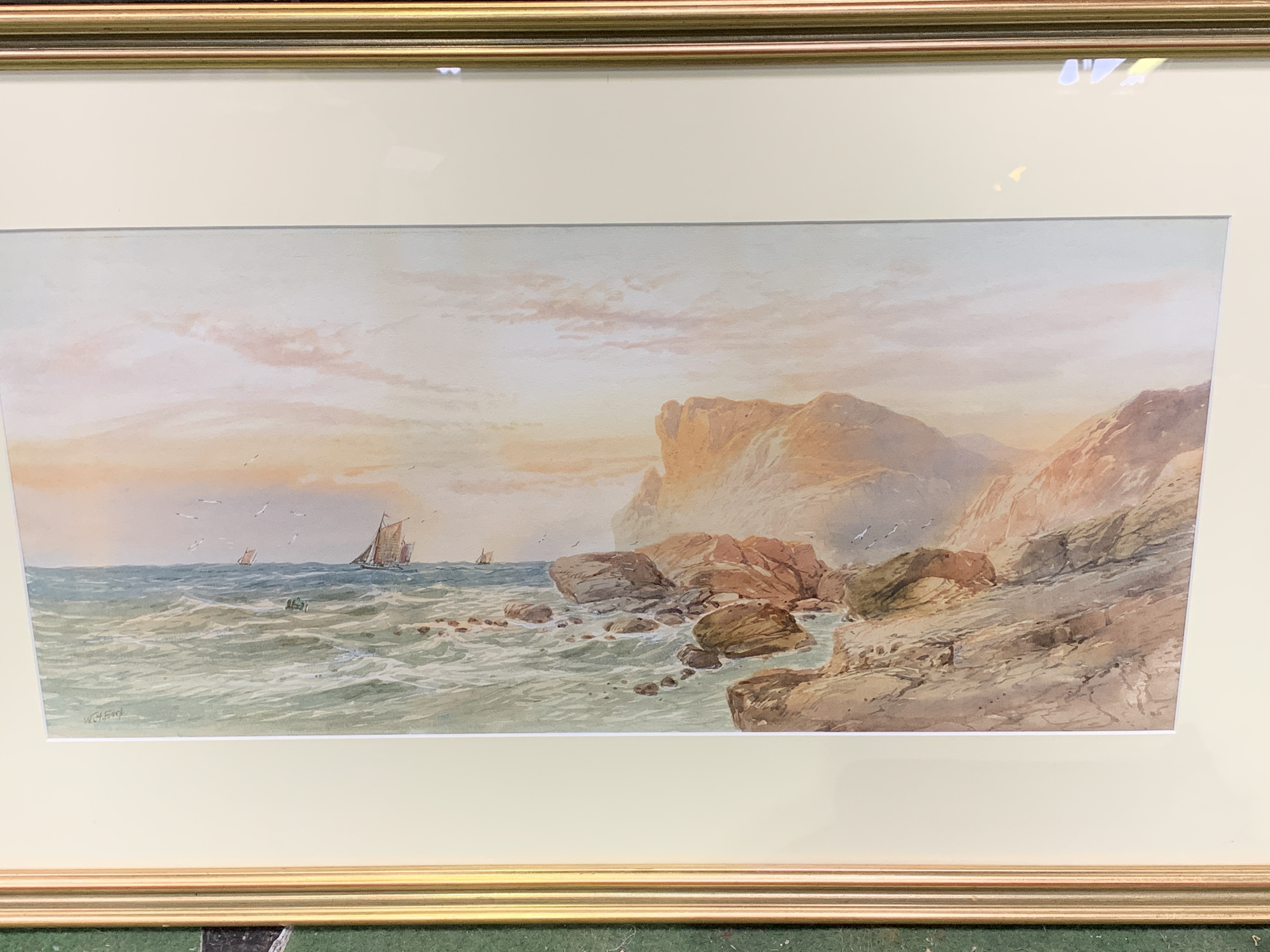 Framed and glazed watercolour of cliffs and sailing ships, signed W H Earp.