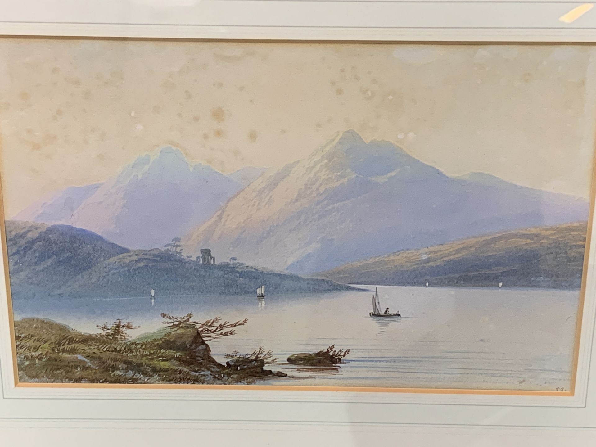Gilt framed and glazed watercolour of boats on a lake with mountains, (foxed), signed monogram E E