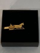 Yellow metal tie clip of a trotter and vehicle