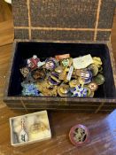 A wooden box containing a quantity of lapel badges and brooches