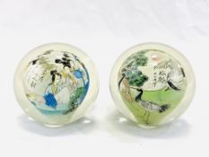 Two reverse painted Japanese glass paperweights, painted with cranes and a village scene