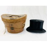 A silk top hat together with a leather hat box