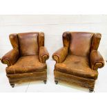 A pair of French brown leather wing back armchairs