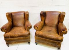 A pair of French brown leather wing back armchairs