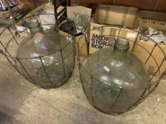 Two large demijohns in metal wire baskets