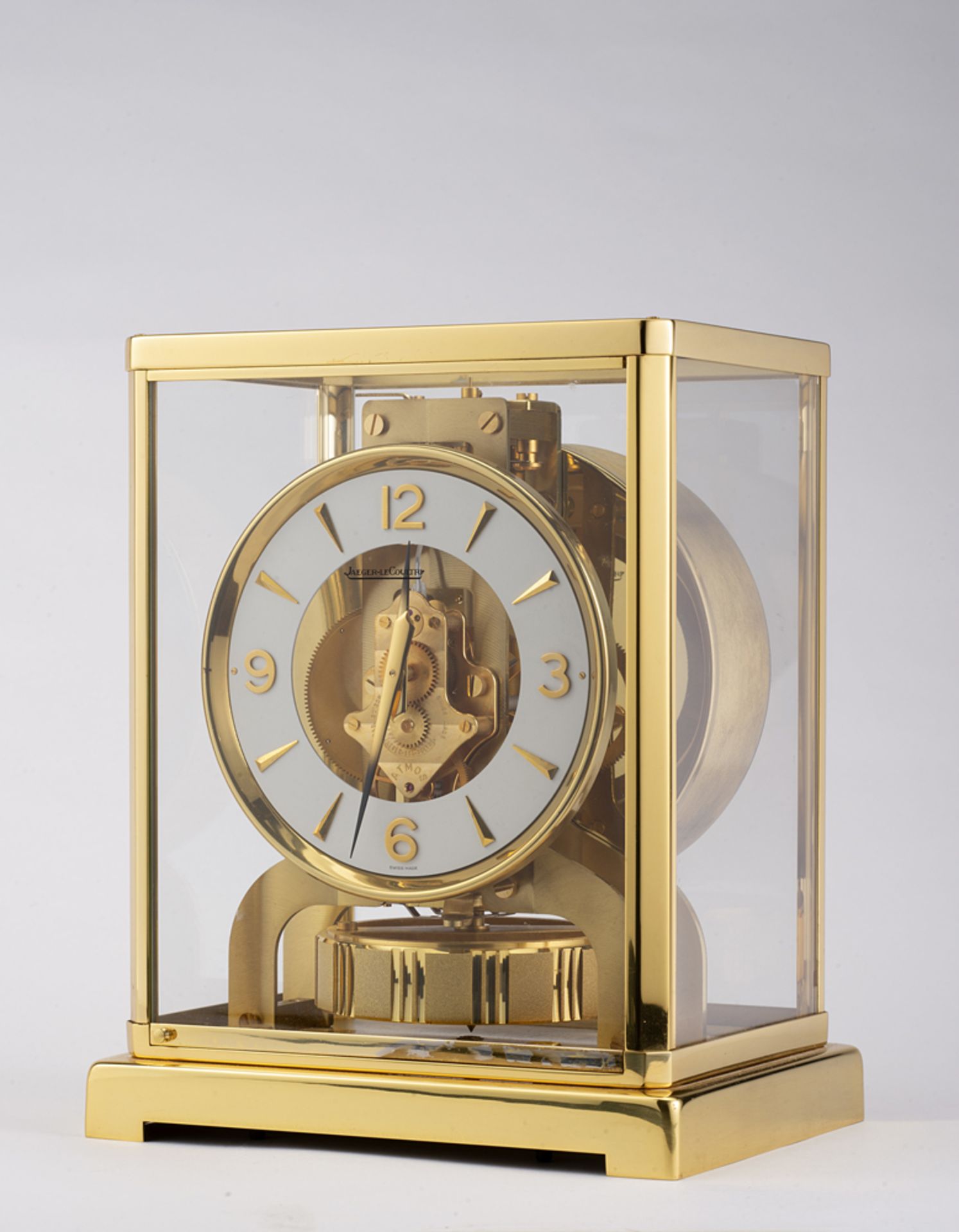 JAEGER LE COULTRE<br>Atmos brass and glass table clock.<br>White dial with Arabic numerals and appli