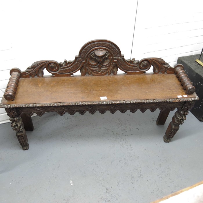 An antique oak bench, carved mask back and bobbin