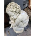 A precast garden figure of a young boy seated on a ball, height 64cm