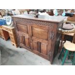 A 17th century style two door carved and panelled oak cupboard on turned supports, 142cm wide, 119cm