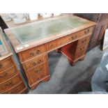 A yew wood twin pedestal writing desk of nine drawers, 120cm wide