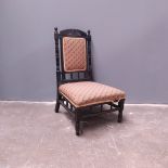 An Aesthetic Movement ebonised fireside chair, circa 1880, arched top rail with carved sunflower