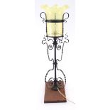 An Arts & Crafts wrought iron uplighter, circa 1895, the scrollwork frame supporting a vaseline