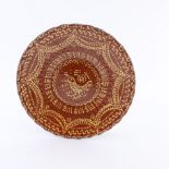 A Staffordshire slipware circular pottery dish, circa 1800, central image of a primitive bid and sun