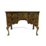 A George III walnut lowboy, circa 1770, crossbanded moulded top over a central frieze drawer with