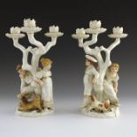 James Hadley for Royal Worcester, a pair of triple branch candelabra in the style of Kate Greenaway,