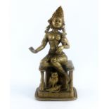 An Indian cast brass figure of the deity Lakshmi, wearing a headdress and seated on a throne with an