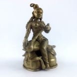 An Indian cast brass figure of a female deity, seated on a lotus leaf playing a string instrument