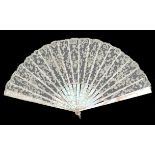 A first quarter 19th century Carrickmacross needle lace fan, the crisp leaf mounted on pink Mother o