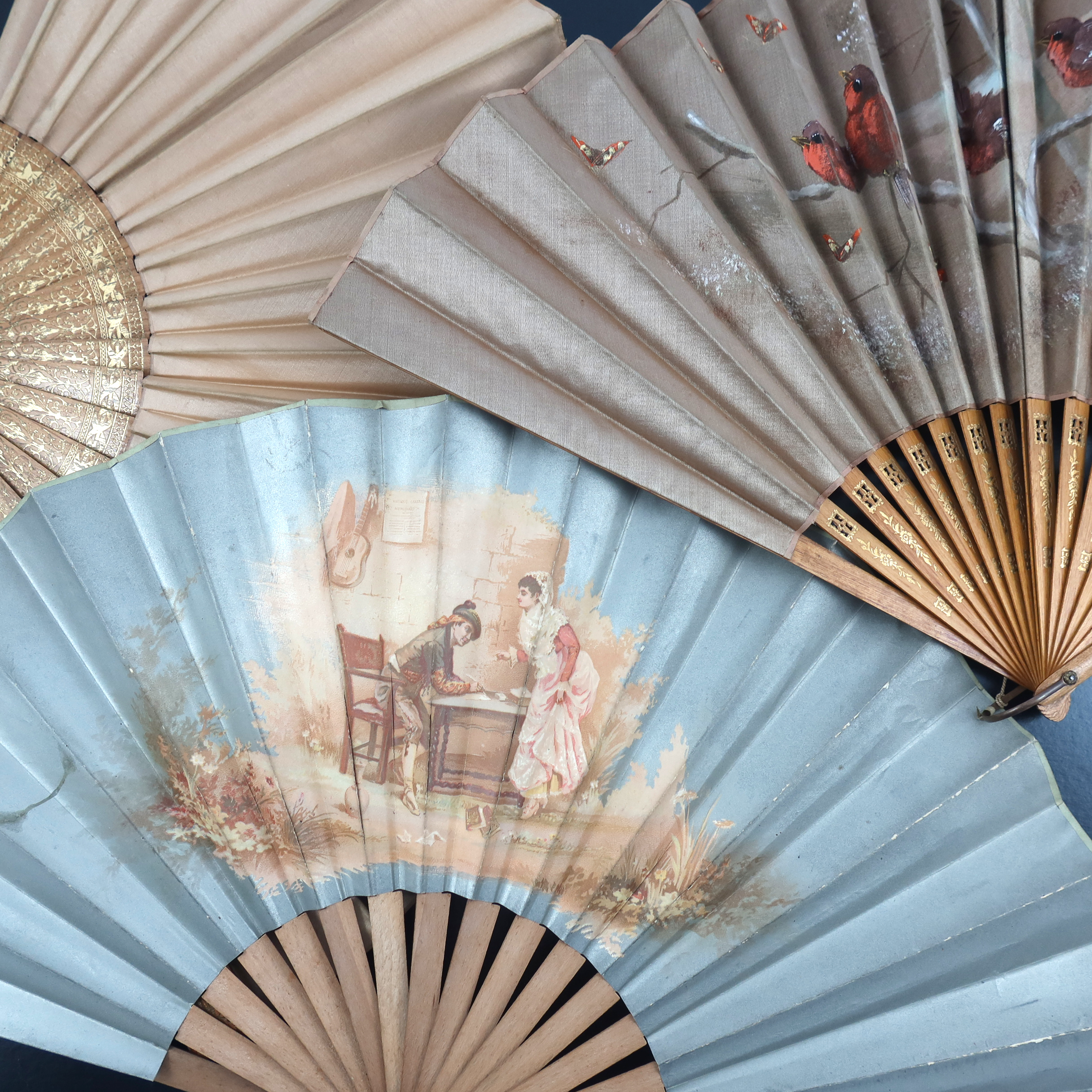 Three large wood fans from the 1890’s, the first with simple gilding to the monture, the taupe silk