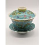 A Chinese turquoise ground famille rose porcelain tea cup with lid and saucer with stylised dragon