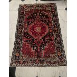 An Afghan red and navy ground rug/carpet, 195cm x 125cm