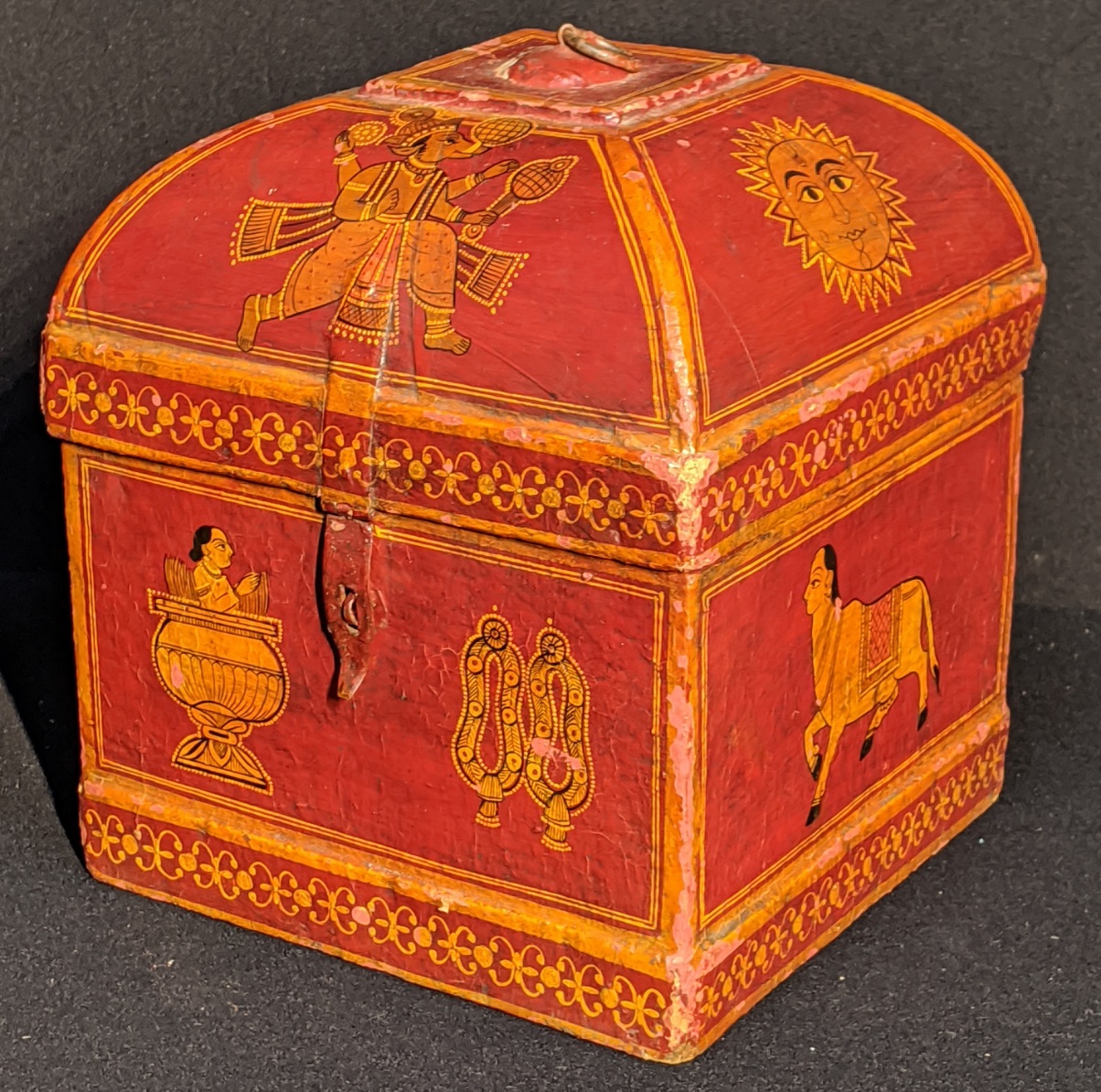 An Indian papier mache turban box, red ground depicting gods and animals, H.27cm W.25cm D.25cm